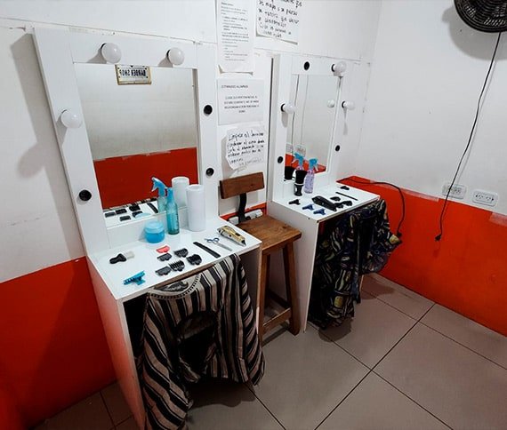 Estación de trabajo de peluquería con espejos iluminados, herramientas de estilismo.
