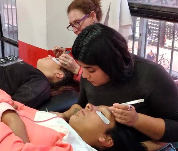 Personas recibiendo tratamientos faciales en un centro de belleza, con profesionales trabajando cuidadosamente y un fondo que incluye una ventana con vista al exterior.