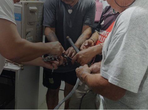 Grupo de personas trabajando en la instalación o reparación de un sistema de tuberías de aire acondicionado en una clase.